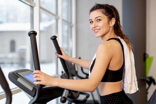 Foto vista lateral sonriente mujer en cinta de correr