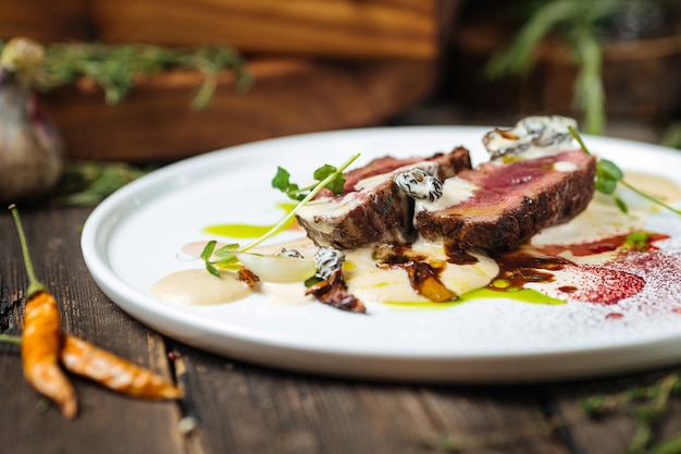 Vista lateral de stroganoff de carne italiana con puré de papas con champiñones en un plato blanco plano sobre la mesa de madera oscura