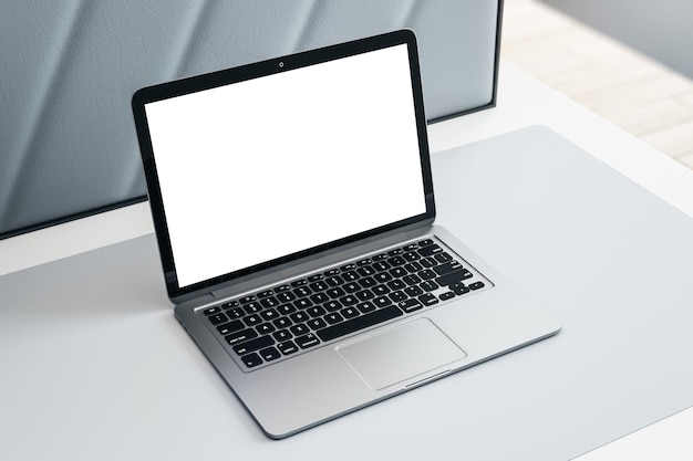 Vista lateral superior en una computadora portátil moderna con pantalla blanca en blanco con lugar para su logotipo o texto en la superficie de la mesa gris claro simulacro de representación 3D