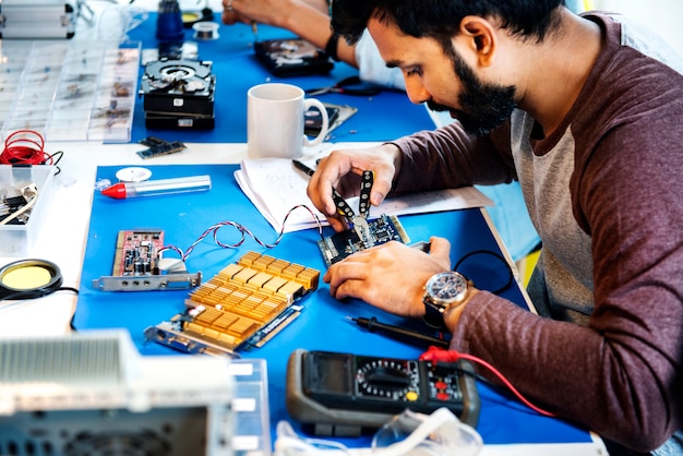 Vista lateral de técnicos que trabajan en piezas de electrónica de computadoras.