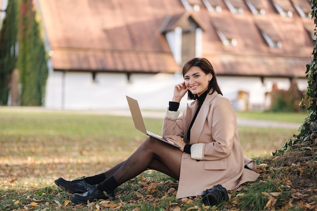 Vista lateral de un trabajador independiente con estilo que trabaja al aire libre mujer que usa una computadora portátil día soleado en Europa