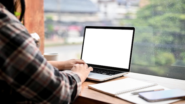 Vista lateral Uma freelancer asiática trabalhando remotamente na cafeteria usando um laptop