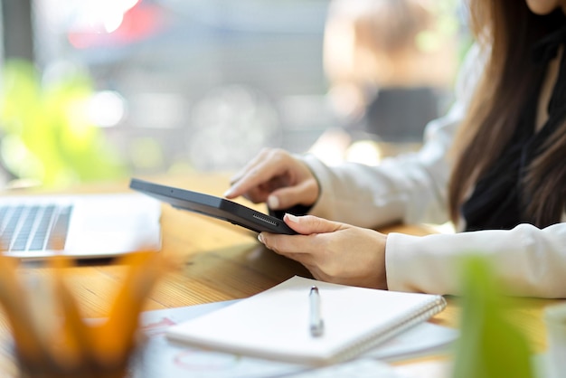 Vista lateral, uma trabalhadora usando o touchpad digital tablet na mesa de trabalho de madeira no escritório.