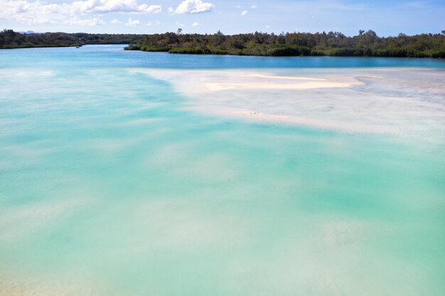 Una vista desde lo alto de una playa tropical y olas rompiendo en una playa tropical de arena dorada. Las olas del mar serpentean suavemente a lo largo de la hermosa playa de arena.