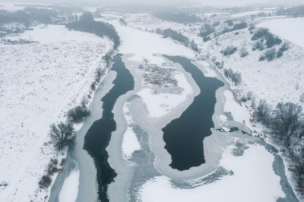 Vista desde lo alto de un río congelado cubierto de nieve Invierno frío Hermosos patrones de hielo en el río desde arriba