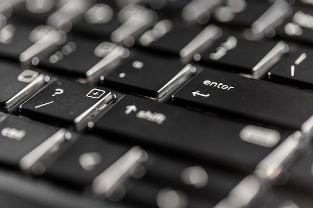 Vista macro de los botones negros del teclado del portátil contra la luz de fondo