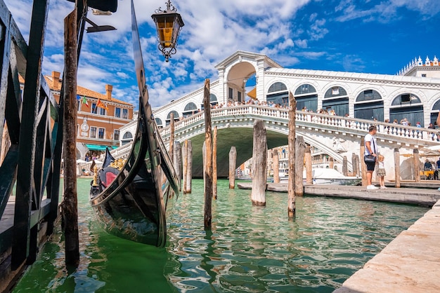 Vista mágica da tradicional gôndola perto do mundialmente famoso Canal Grande e a ponte de Rialto ao pôr do sol em Veneza, Itália. Filtro retro vintage do Instagram e efeito de reflexo adicionados.