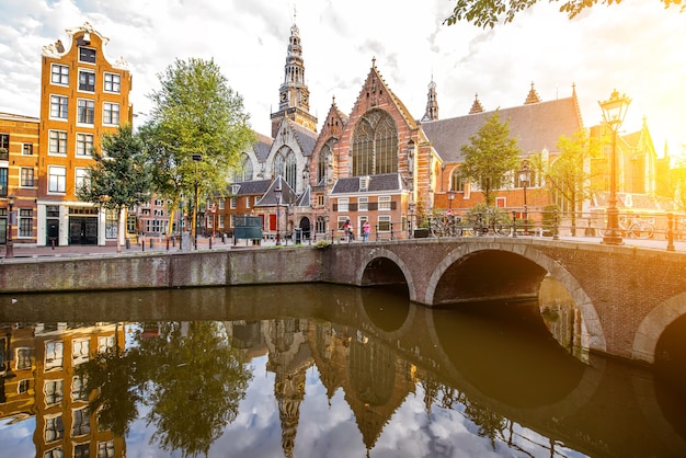 Vista de la mañana sobre el canal de agua con la Iglesia Vieja durante el clima soleado en la ciudad de Amsterdam