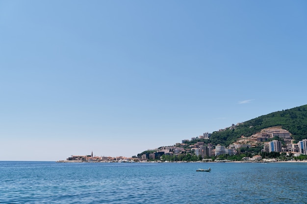 Vista desde el mar a los edificios de budva entre la vegetación de las montañas