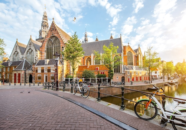 Vista matinal no canal de água com a velha igreja durante o tempo ensolarado na cidade de Amsterdã