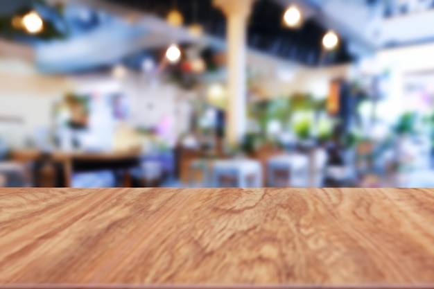 Vista de mesa de madera vacía con luz bokeh en restaurante borroso