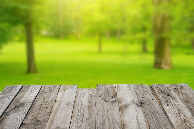 Vista desde la mesa de la terraza de madera vacía al fondo verde del bokeh del follaje de primavera