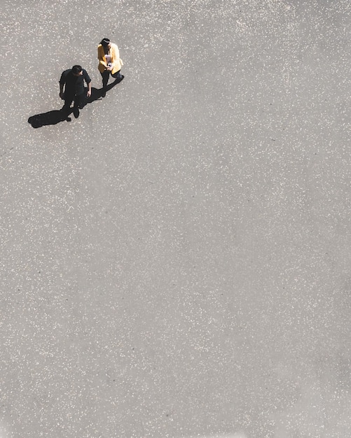Foto vista minimalista en ángulo alto de dos personas en el suelo de hormigón