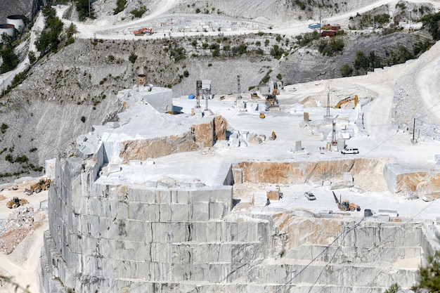 Vista mirando hacia abajo un valle de cantera de mármol en Carrara, Toscana, Italia mostrando bloques de piedra cortada y una pared de roca en terrazas en la minería a cielo abierto