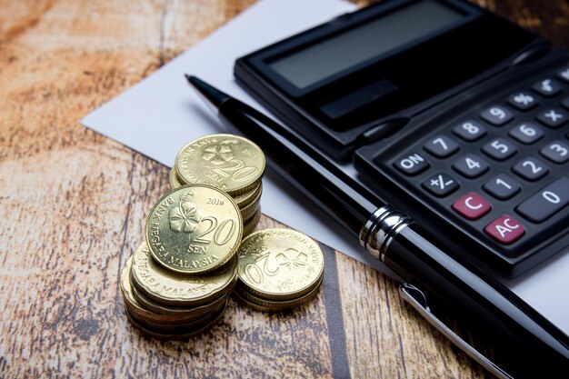 Vista de las monedas en ángulo alto con calculadora y bolígrafo en la mesa