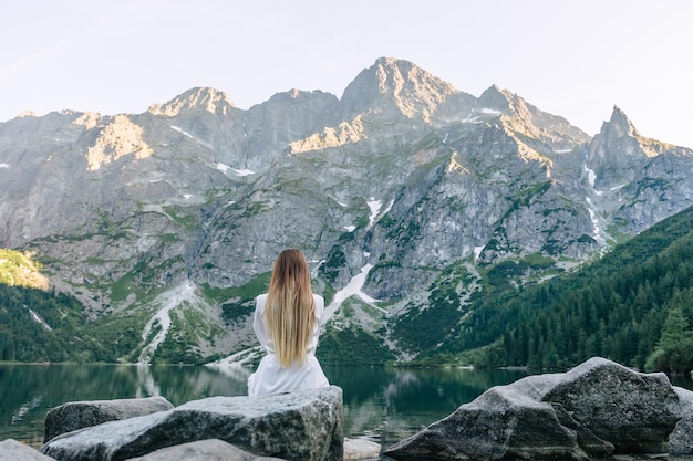 Vista de las montañas rocosas y el lago vista trasera de una chica en blanco