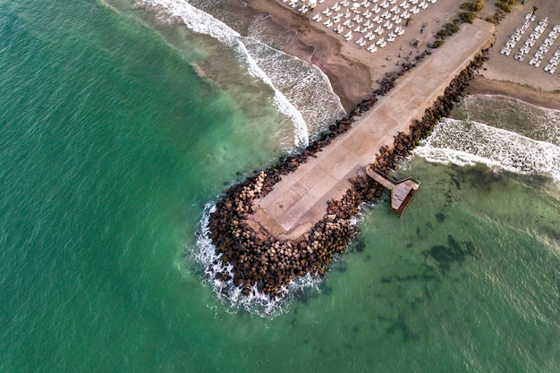 Vista de un muelle de hormigón con olas rompiendo en las piedras.