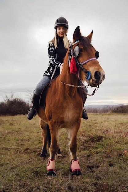 Vista de una mujer con casco montando caballos en el campo
