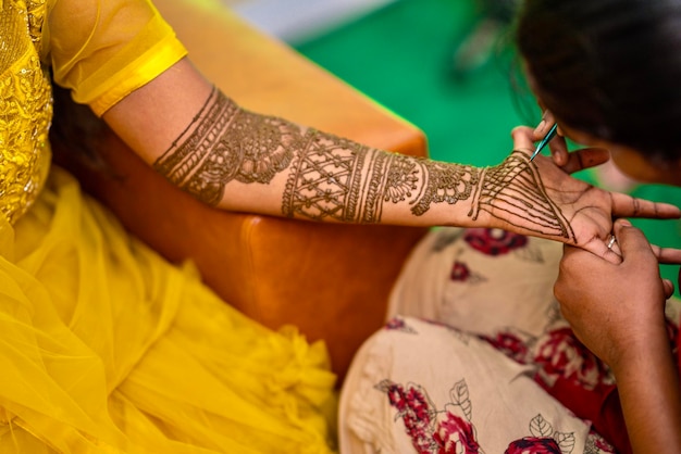 Vista de una mujer dibujando el arte corporal tradicional de Henna Mehandi en una mano