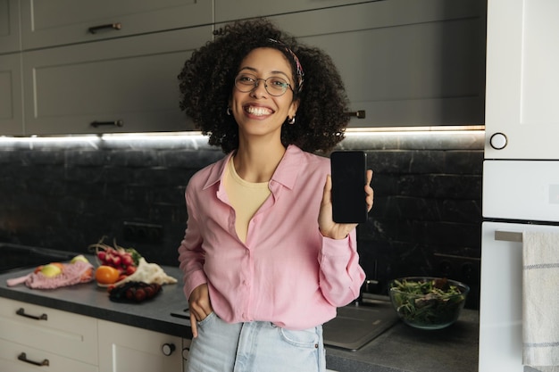 Vista de mujer de sonrisa negra mostrando su teléfono a la cámara