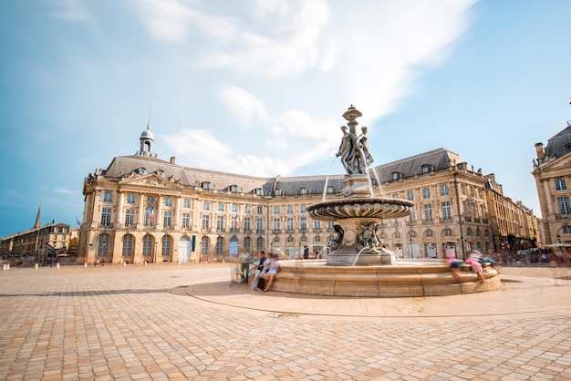 Vista na famosa praça la bourse com fonte na cidade de bordéus, frança. técnica de imagem de longa exposição com movimento borrado de pessoas e nuvens