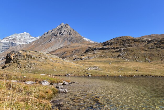 Vista no lago no Parque Nacional de Vanoise, na França, com fundo de montanhas nevadas sob o céu azul