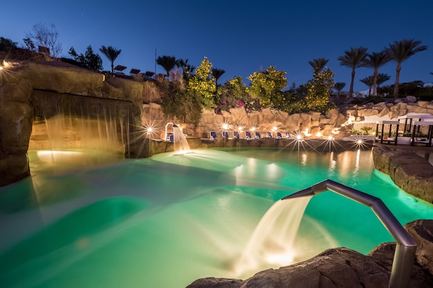 Vista de noche para piscina de lujo con iluminación nocturna