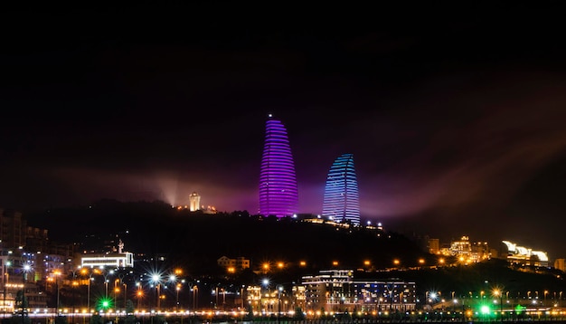 Foto vista nocturna de bakú con la torre de televisión de rascacielos y la costa del mar caspio