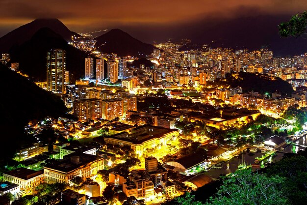 Vista nocturna del barrio de Botafogo en Río de Janeiro con colinas de luces de la ciudad