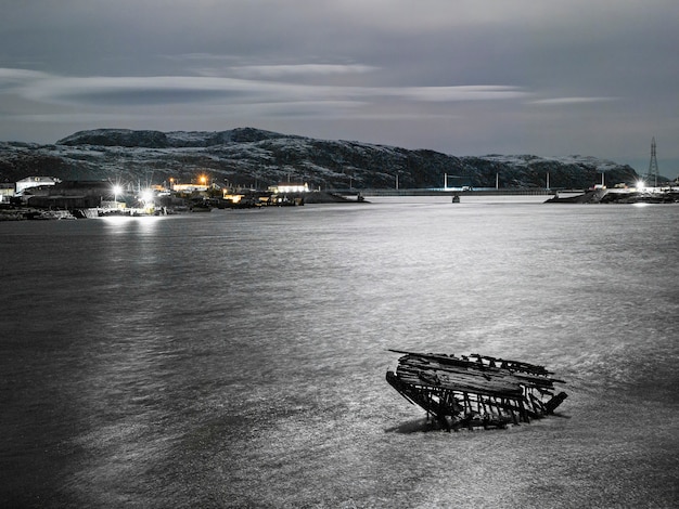 Vista nocturna del cementerio de barcos, antiguo pueblo de pescadores en la orilla del mar de Barents, la península de Kola