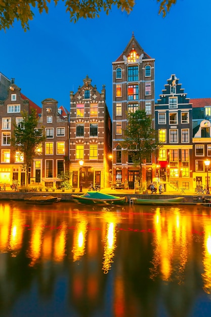 Vista nocturna de la ciudad del canal Herengracht de Amsterdam, casas y barcos típicos holandeses, Holanda, Países Bajos.