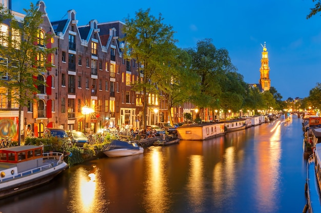 Vista nocturna de la ciudad del canal Prinsengracht de Amsterdam con casas flotantes y la iglesia Westerkerk, Holanda, Países Bajos.