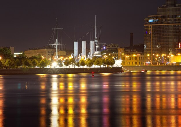 Vista nocturna de la ciudad del crucero Aurora en el terraplén de Petrogradskaya en las luces de la noche