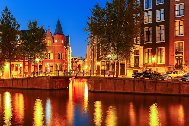 Vista nocturna de la ciudad del puente del canal de amsterdam casas típicas y bicicletas holanda países bajos