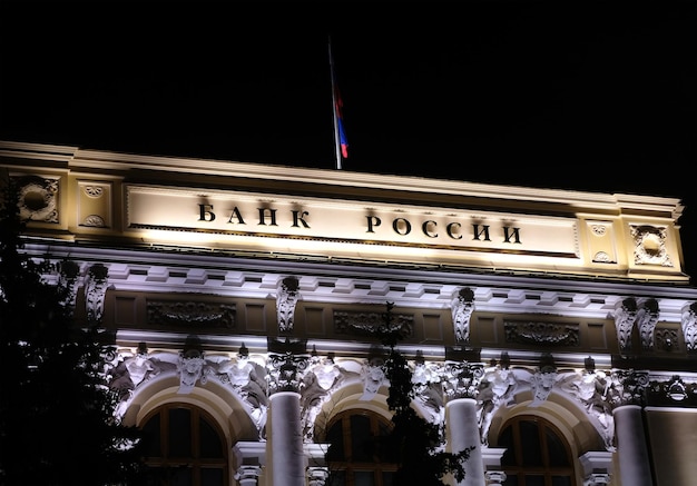 Vista nocturna del edificio del Banco Central de Rusia en Moscú con bandera estatal en la parte superior del techo