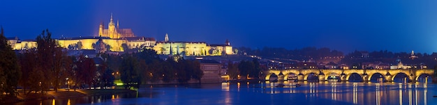 Vista nocturna de la famosa ciudad europea de Praga - la capital de la República Checa con reflejo en el río Vltava y el Puente Carlos. Vista panorámica.