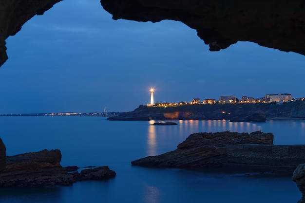 La vista nocturna del faro de Biarritz visto a través del arco de roca Francia