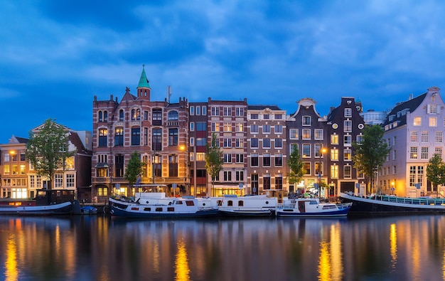 Vista noturna da cidade de casas e barcos holandeses típicos do canal de Amsterdã Holanda Holanda