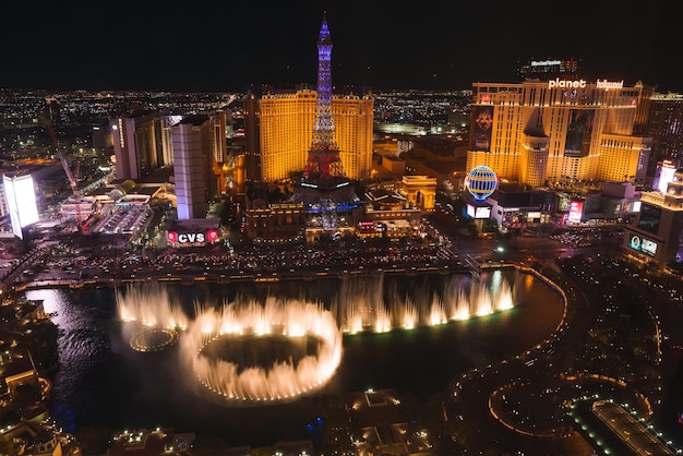 Foto vista noturna vibrante da icônica strip de las vegas com fontes bellagio e réplica da torre eiffel