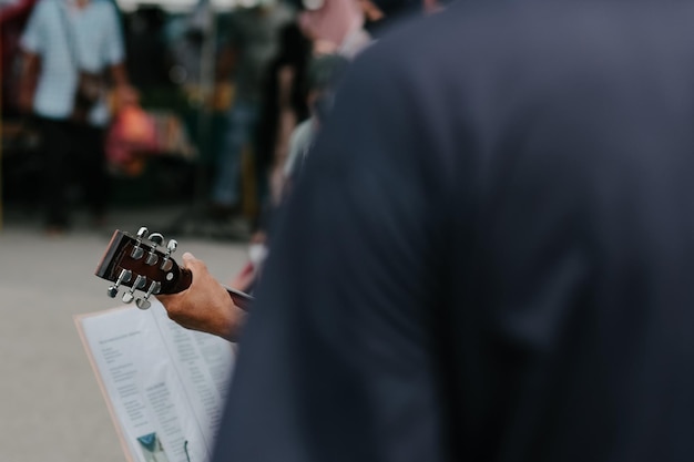 Foto vista oculta de un músico de la calle tocando la guitarra en un mercado