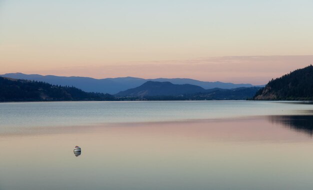 Vista pacífica del lago de madera con reflejo en el agua y las montañas en segundo plano.