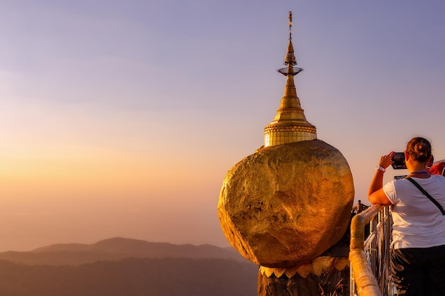 Vista de la Pagoda Kyaiktiyo al atardecer. Roca dorada. Birmania. Turista tomando una foto con su teléfono