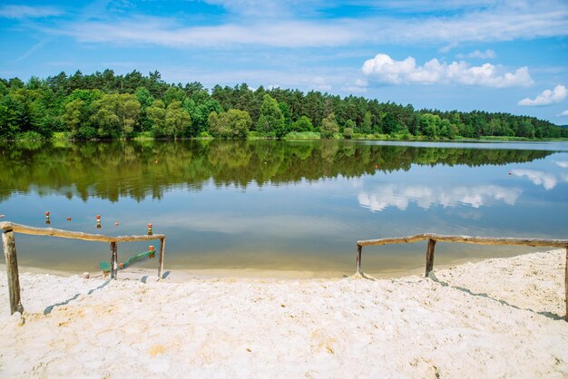 Vista paisagística do lago em um dia de verão ensolarado reflexo do céu na praia de areia de água