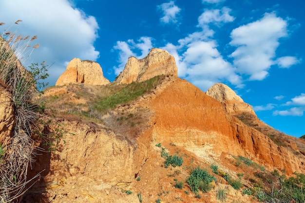 Vista del paisaje acantilados del cabo de arcilla. Hierba verde, césped cultivado en laderas de montañas de arcilla contra el cielo azul. Las colinas de montaña y las laderas del cabo están cubiertas de hierba y plantas. Muro de arcilla.