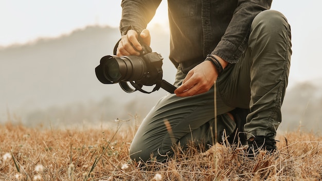 Vista del paisaje de disparo, cerca del joven fotógrafo masculino asiático durante la celebración de la cámara