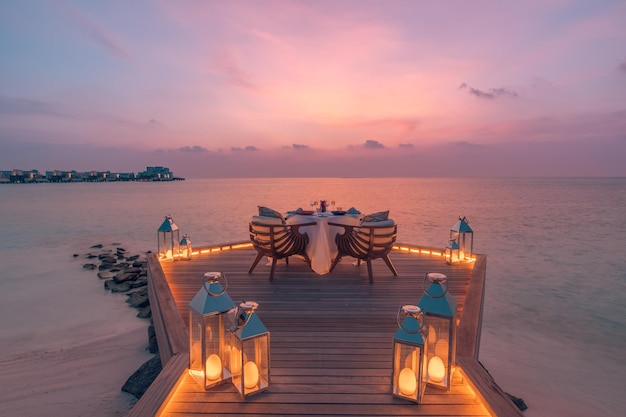 Vista del paisaje marino, luz de puesta de sol con mesa de comedor con reflejo de piscina infinita. escapada romantica en pareja