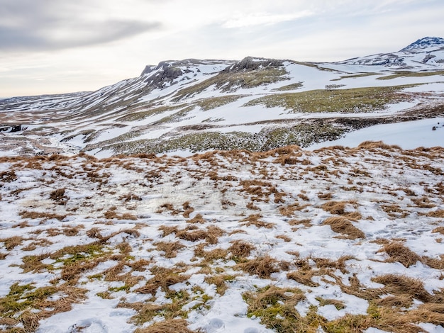 Vista del paisaje con nieve en la temporada de invierno bajo un cielo nublado a lo largo del camino en Islandia