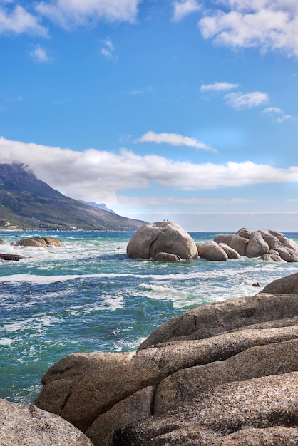 Vista del paisaje de rocas de agua de mar y un cielo azul con espacio de copia en Camps Bay Beach Ciudad del Cabo Sudáfrica Tranquilo océano tranquilo y relajante paisaje natural Olas que se lavan en la costa rocosa