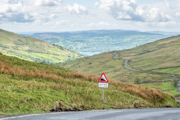 Vista del paisaje rural de árboles verdes y hierba con montaña a lo largo de un camino estrecho en la Inglaterra rural