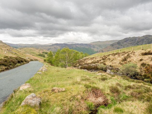 Vista del paisaje rural de campo verde y fondo de montaña bajo un cielo nublado en Inglaterra